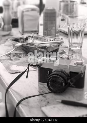 Al bancone della cucina, un fotografo mangiava in fretta. Bianco e nero, tasto alto. Foto Stock