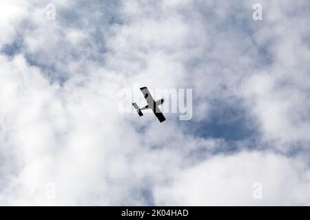 Velivoli leggeri vola in cielo nuvoloso su una foto di giorno, silhouette Foto Stock