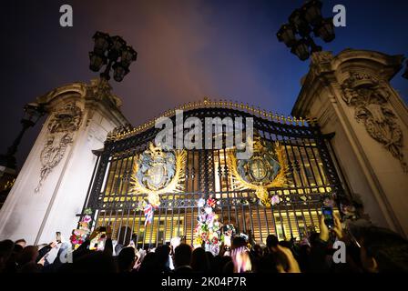 Londra, Regno Unito. 09th Set, 2022. Centinaia di persone camminano lentamente oltre l'ingresso principale di Buckingham Palace decorato con fiori e messaggi di lutto. La regina britannica Elisabetta II morì il 08.09.2022 all'età di 96 anni. Credit: Christian Charisius/dpa/Alamy Live News Foto Stock