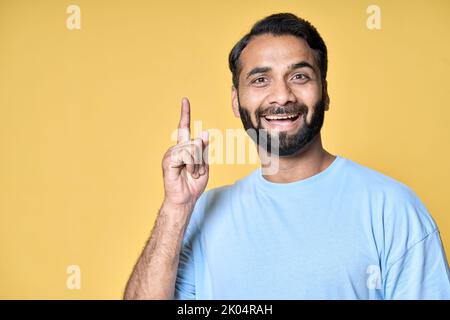 Felice eccitato indiano uomo puntando dito ha ottenuto nuova grande idea isolato sul giallo. Foto Stock
