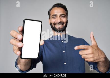 Uomo d'affari indiano felice che indica lo schermo del telefono cellulare mockup. Foto Stock