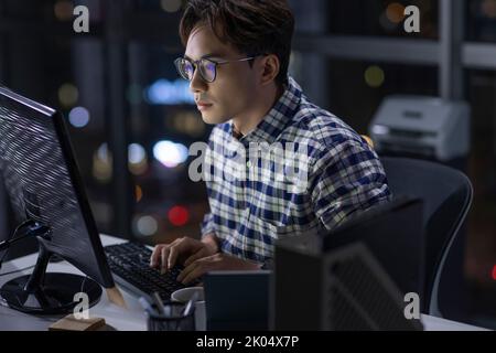 Lavoratore IT cinese che lavora in ufficio di notte Foto Stock