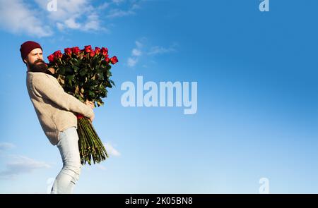 Uomo con bouquet di fiori di rose. Happy man tiene un grande bouquet di rose rosse, proporre al fidanzato in data. Romantico ragazzo celebrare San Valentino. Foto Stock