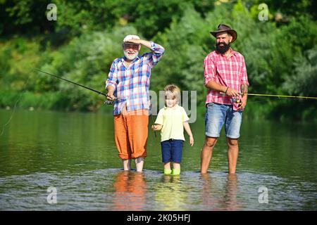 Hobby e attività sportive. Uomo che insegna ai bambini come pescare nel fiume. Buon nonno, padre e nipote con canne da pesca sul ormeggio del fiume. Foto Stock