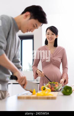 Donna incinta cinese felice e marito che cucinano in cucina Foto Stock