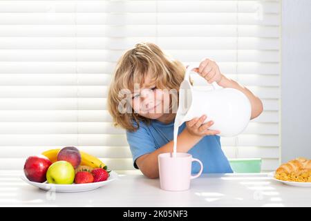 Capretto che versa latte intero di mucche. Ritratto di bambino presteen mangiare cibo fresco sano in cucina a casa. Bambino che mangia la colazione prima della scuola. Vitamina Foto Stock