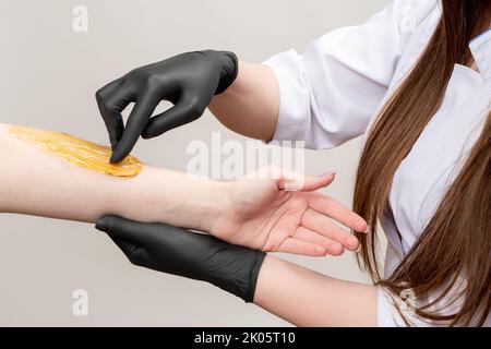 braccio depilazione miele ceretta estetista femminile Foto Stock