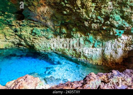 Vista della splendida piscina naturale di acqua cristallina formata in una grotta rocciosa con stalagmiti e stalagmiti. Caverna di Kuza a Zanzibar, Tanzania Foto Stock