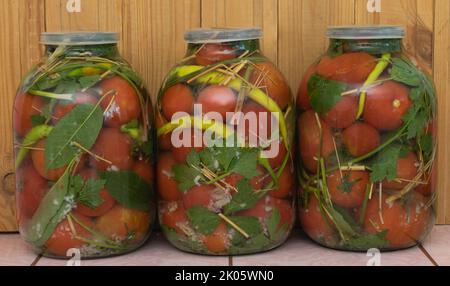 Qualche vasetto di pomodori marinati, ricetta concetto. Pomodori marinati freschi fatti in casa su sfondo di legno Foto Stock