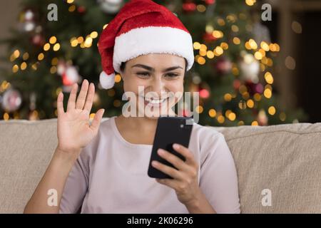 Ragazza indiana felice in cappello di Natale parlando in videochiamata Foto Stock