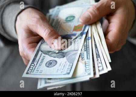 Il modello femminile bianco mostra le fatture del dollaro nella sua vista anteriore del primo piano della mano Foto Stock