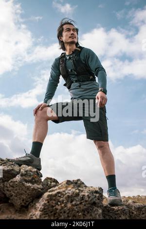 Corridore cinese maschio in piedi sulla roccia Foto Stock