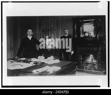 Tre dipendenti del Dipartimento del Tesoro, MR. Graham, John Brown, e un altro uomo, posato in un ufficio con un camino, tra il 1884 e il 1930. Foto Stock