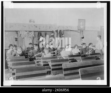 Carlisle, tra le 1901 e le 1903. Classe presso la Indian Industrial School di Carlisle, Pennsylvania, mostrando agli insegnanti di osservare gli studenti che leggono. (Scuola superiore per studenti dei nativi americani, fondata nel 1879 sotto l'autorità governativa degli Stati Uniti. Studenti maschi e femmine in classe. Si notano oggetti di abbigliamento tradizionale attaccati al muro, e disegni di tipi sulla lavagna). Foto Stock