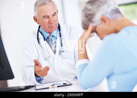Il medico discute i rapporti con il paziente infelice. Concentratevi sul medico maturo che discute il rapporto medico con il paziente infelice. Foto Stock