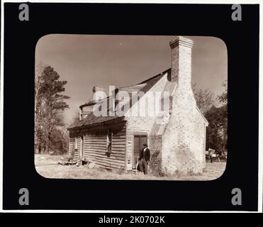 Huggins House, Lynnhaven Village, Princess Anne County, Virginia., tra il c1930 e il 1939. Uomo afroamericano in piedi dal camino di una casa costruita nel 17th ° secolo. Foto Stock