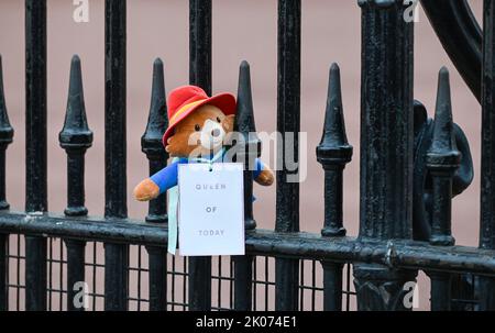 Londra UK 10th settembre 2022 - un orso di Paddington è lasciato sulle ringhiere mentre la folla paga i loro rispetti e continua a portare i fiori fuori Buckingham Palace a Londra oggi dopo la morte della regina Elisabetta II . Re Carlo III è stato anche proclamato monarca oggi : Credit Simon Dack / Alamy Live News Foto Stock