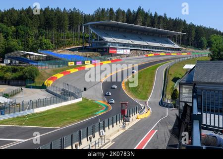 Vista di quattro auto da corsa che corrono attraverso la pericolosa curva di Eau Rouge sulla rampa di accesso Raidillon alta 40 metri del Circuit de Spa Francorchamps, nel Foto Stock