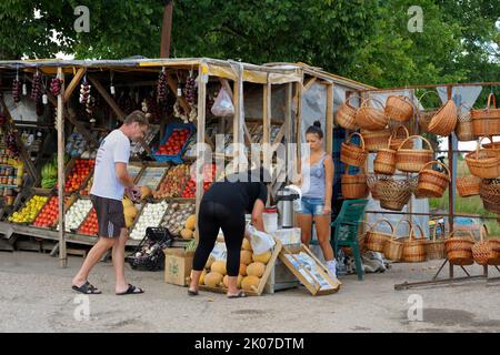 Ragazza giovane venditore di strada che vende verdure ai clienti, cesti di vimini, mercato alimentare a bordo strada. Giugno 10, 2017. Simferopol - Kyiv autostrada vicino a Jankoy, Foto Stock