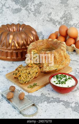 Cucina sveva, dolce svizzero con salsa alle erbe, formaggio riccio, pasticceria sostanziosa su tavola di legno, torta salata, vegetariana, cottura, grattugia alla noce moscata Foto Stock