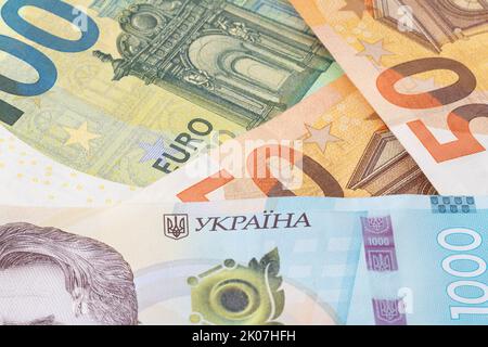 Primo piano di un migliaio di banconote ucraine hrivnya contro diverse banconote in euro Foto Stock