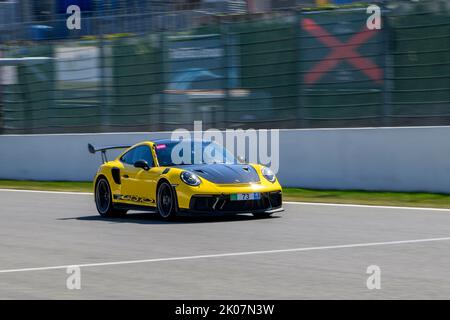 Auto da corsa gialla auto sportiva Porsche 911 GT3 RS corre ad alta velocità massima durante la giornata di pista sulla partenza-arrivo dritto inizio-fine della pista di gara Foto Stock