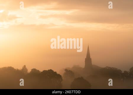 Il campanile della chiesa di St Barnabas a Weeton si trova all'alba in una mattina d'estate nebbiosa. Foto Stock