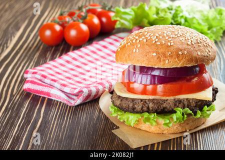 Cheeseburger fatto in casa con polpette di manzo e insalata fresca su panini stagionati, salato su tavolo di legno marrone. Foto Stock