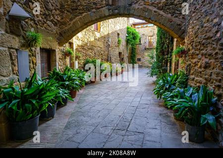 Passaggi con portici in pietra e case medievali in uno stile pittoresco e di grande bellezza, Monells, Girona, Catalogna. Foto Stock