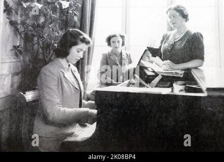 La principessa Elisabetta suona il pianoforte mentre sua madre, la regina Elisabetta, e la sorella, la principessa Margaret, guardano sopra Foto Stock