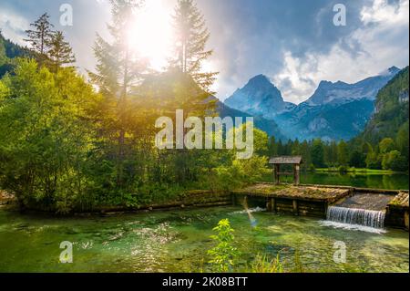Famoso lago verde Schiederweiher vicino al villaggio di Hinterstoder. Piccolo stramazzo e diga sul lago con acqua corrente. Grandi montagne austriache sullo sfondo. Morbido Foto Stock