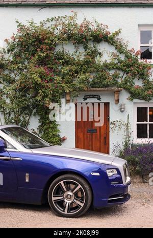 Blu e argento Rolls Royce Dawn convertibile parcheggiato fuori casa di campagna Foto Stock