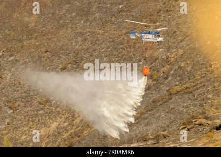 Elicottero contro gli incendi, effettuando uno scarico d'acqua. Foto Stock