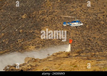 Elicottero contro gli incendi, effettuando uno scarico d'acqua. Foto Stock