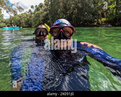 Una coppia che si diverte a fare snorkeling in acqua limpida prendendo un selfie. Foto Stock