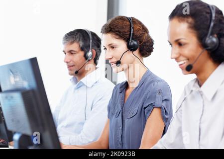 Le vostre soluzioni sono disponibili 247. Profilo di un gruppo di professionisti del call center che lavorano al computer. Foto Stock