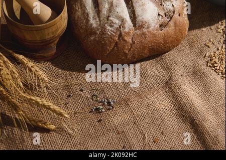 Vista dall'alto. Tradizionale pane di grano saraceno a pasta madre, su una tovaglia di lino accanto ad un mortaio di legno e alle orecchie di grano Foto Stock