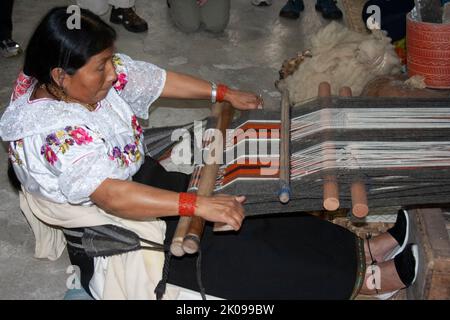 Tessitori al lavoro su telai a mano che fanno oggetti come tappeti o abbigliamento, nel mercato di Otavalo negli altopiani andini a nord di Quito Ecuador Foto Stock
