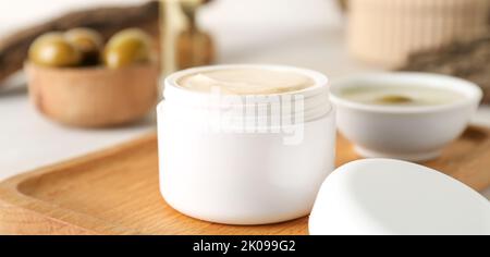 Vasetto di panna con estratto di olio d'oliva sulla tavola, primo piano Foto Stock