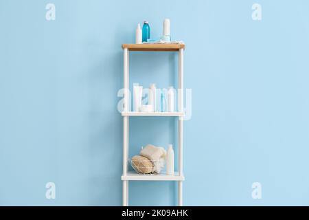 Scaffale con diversi accessori per bagno vicino alla parete colorata Foto Stock