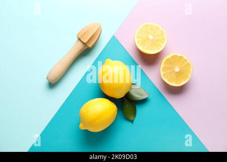 Limoni maturi e centrifuga in legno su sfondo colorato Foto Stock