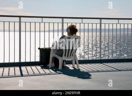 Rilassarsi e ascoltare musica sul traghetto attraverso il canale Foto Stock