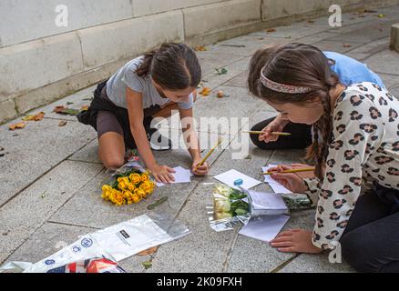 Londra UK 10th settembre 2022 - le ragazze giovani, scrivendo messaggi e fiori in fiore - i lutto si riuniscono a Buckingham Palace mettendo i fiori e pagando i loro rispetti - la regina Elisabetta la seconda è morta ieri nel suo anno Platinum Jubillee a Balmoral Castle. Friedrichs Alamy Live News Foto Stock