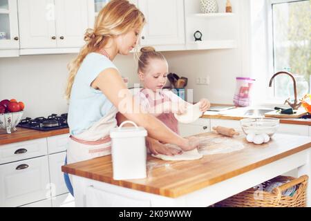 Shes un piccolo fornaio attento. Carina bambina che si cucina con la mamma. Foto Stock