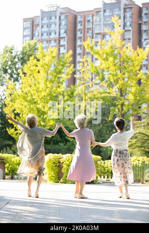 Felici gli amici cinesi che ballano nel parco Foto Stock