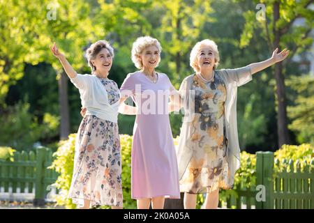 Felici gli amici cinesi che ballano nel parco Foto Stock