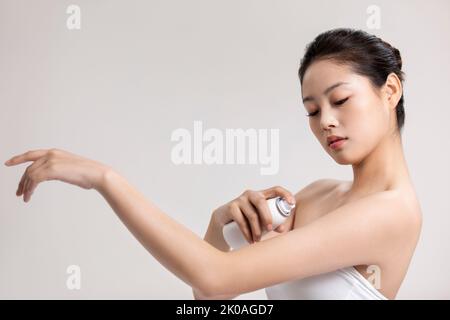 Bella giovane donna cinese che applica idratante Foto Stock