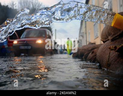 UN LAVORATORE DELL'AMBIENTE ISPEZIONA LE STRADE ALLAGATE DI HAMBLEDON, HAMPSHIRE DOPO UN'ALTRA NOTTE DI PIOGGIA. IL VILLAGGIO È STATO INONDATO PER PIÙ DI DUE SETTIMANE. PIC MIKE WALKER, MIKE WALKER IMMAGINI, 2014 Foto Stock