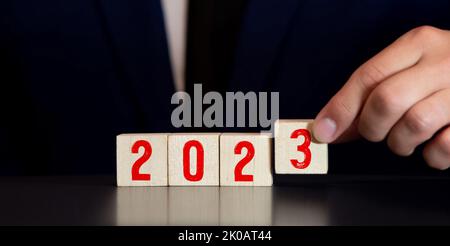 Felice anno nuovo concetto, flipping di blocco di legno cubo cambiare dal 2022 al 2023. Cubo di legno con flip sopra blocco 2022 a 2023 parola. Dirigenti d'affari Foto Stock