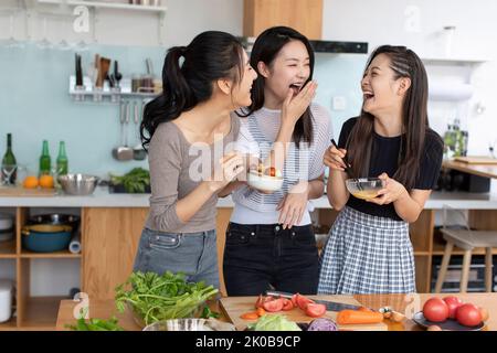 Giovani amici cinesi che cucinano in cucina Foto Stock